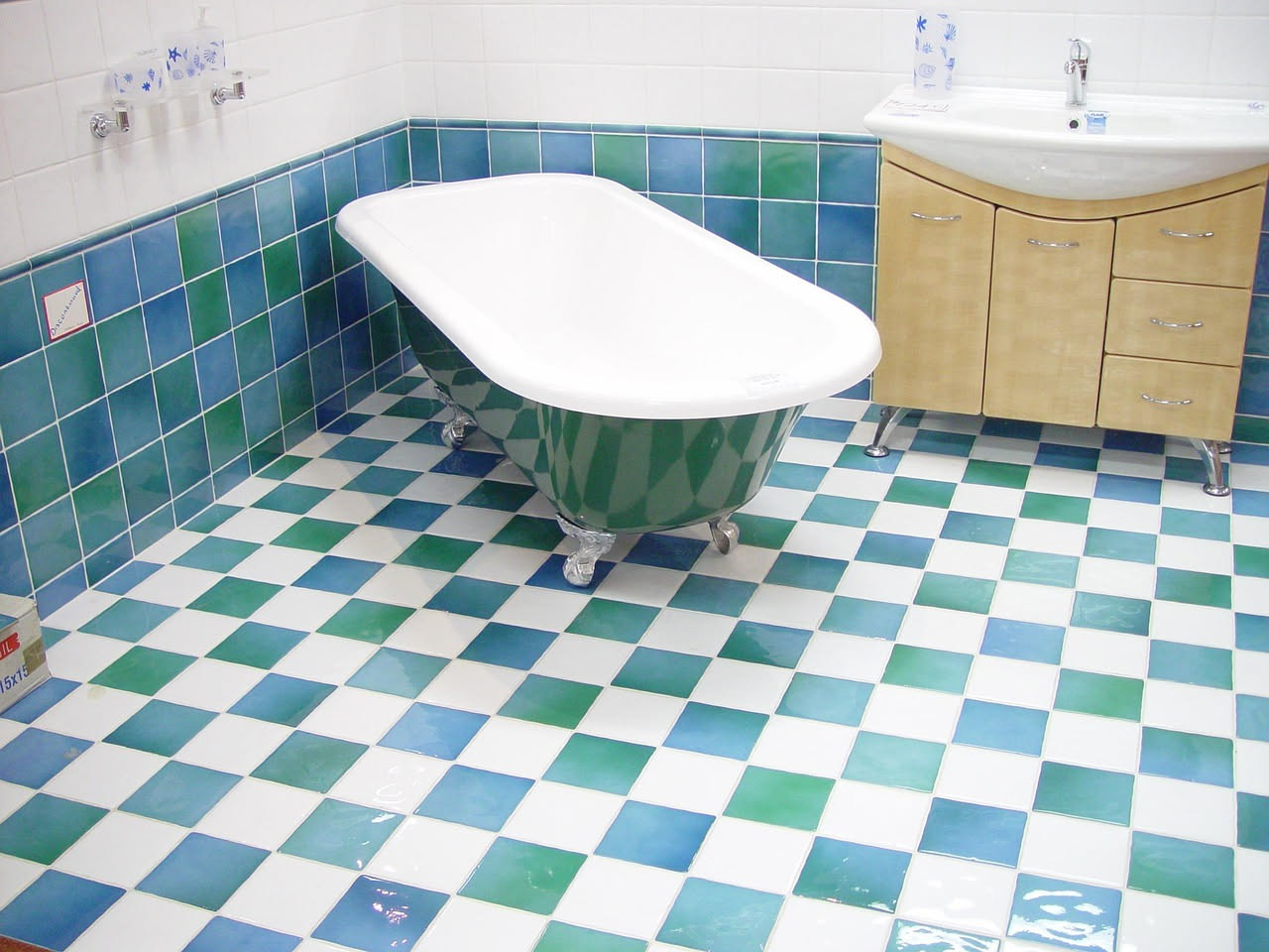 Piastrelle bianche di ceramica lucida in bagno con gocce di aceto bianco in una bottiglia di vetro trasparente su un ripiano grigio