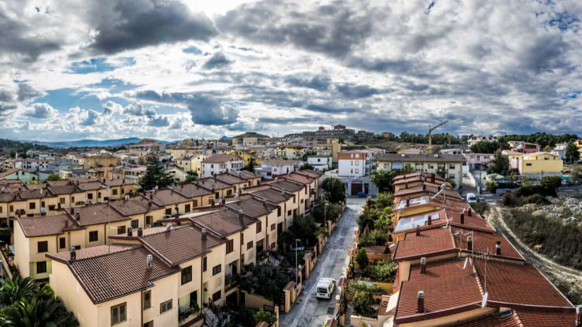 Divano grigio moderno in un soggiorno con pavimento in legno chiaro, finestra con vista esterna e lampada da terra nera