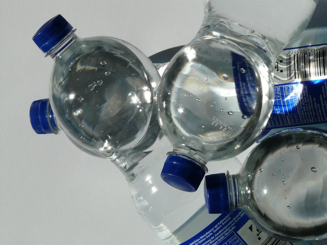 Etichetta bianca e blu appesa a un rubinetto di acciaio con scritte nere che indicano parametri di qualità dell'acqua e informazioni sul trattamento