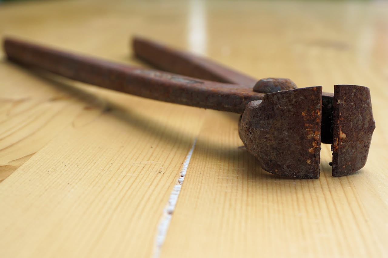 Dettaglio ravvicinato di un bordo di tavolo in legno scuro con una scheggia mancante nel lato esterno del piano