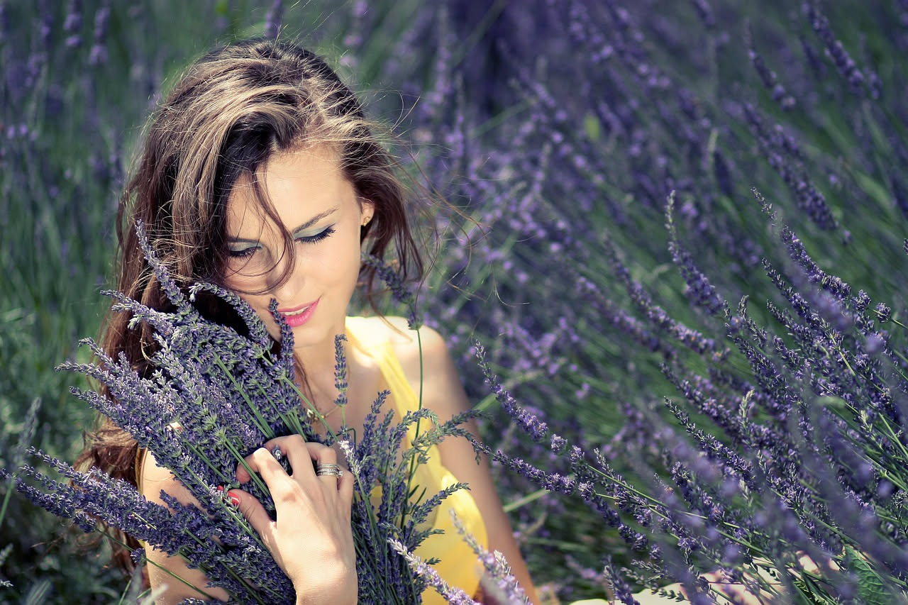 Fiori di lavanda viola e bianchi di gelsomino in un vaso di vetro trasparente su un tavolo di legno in una stanza luminosa