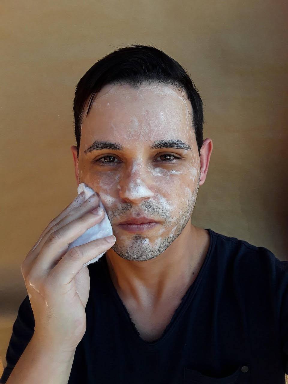 Donna che si lava il viso con acqua fresca al mattino, con gocce di acqua sul viso, specchio del bagno retrostante, light naturale dalla finestra