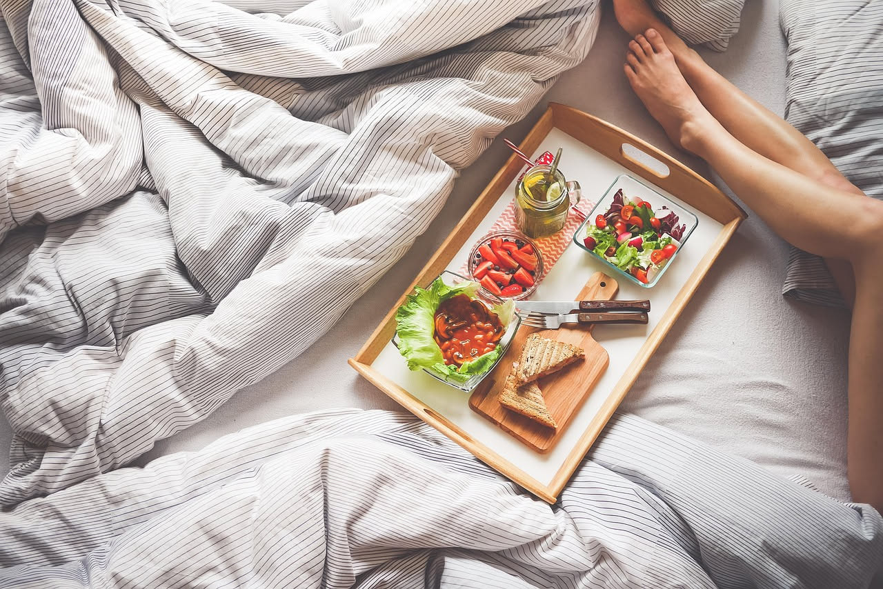Tavolo da pranzo in una cucina naturale con piatto di cibo, bicchiere d'acqua, niente telefono né computer visibili, luce solare da una finestra