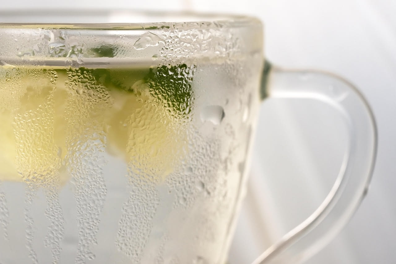 Microonde aperto con una ciotola d'acqua e fette di limone giallo all'interno, vapore bianco che sale dall'interno dell'apparecchio