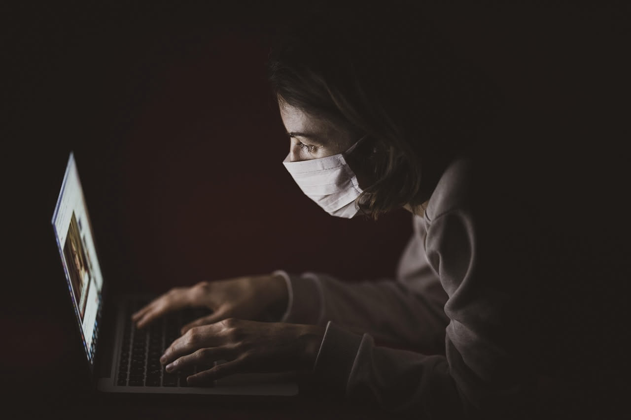 Uomo seduto alla scrivania davanti a un monitor che guarda fuori dalla finestra verso il paesaggio lontano, con le mani abbandonate sulla tastiera