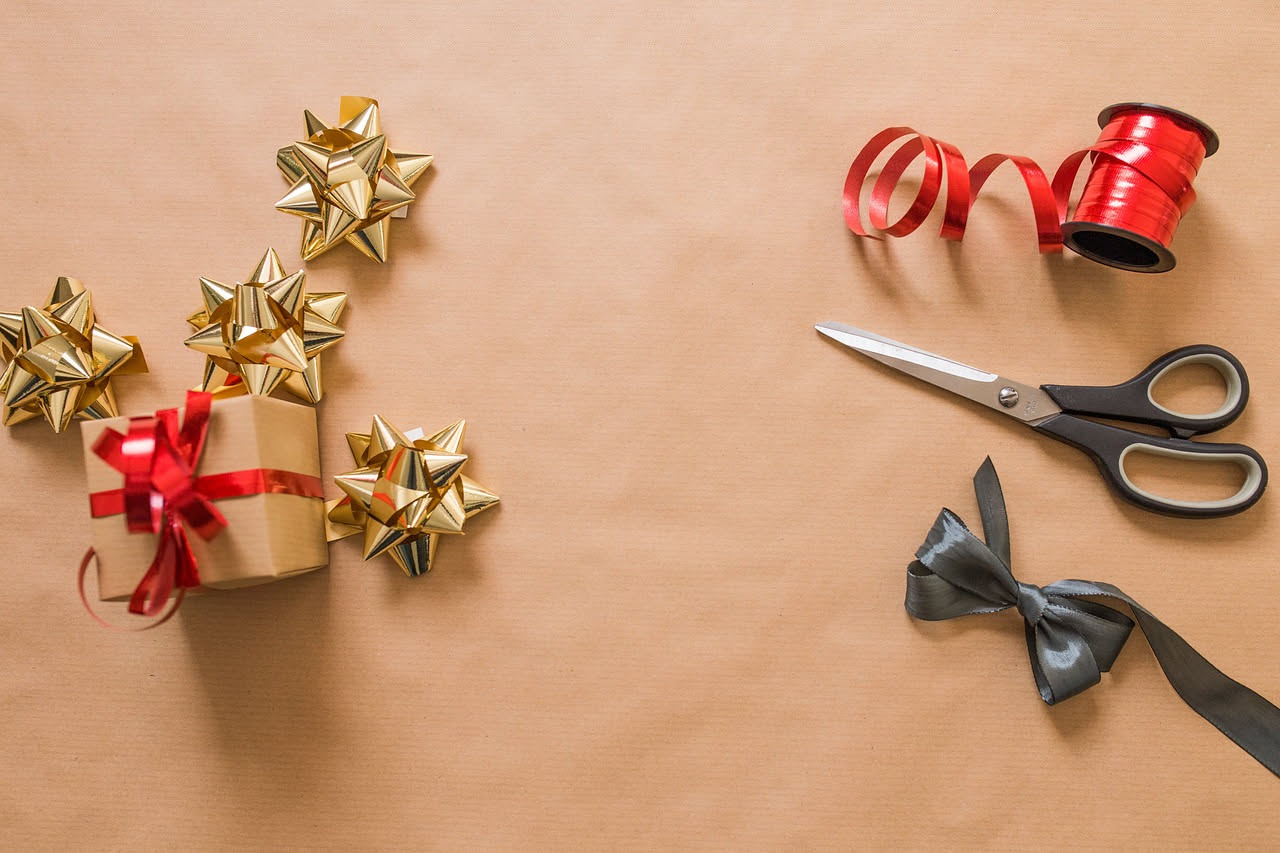 Rotolo di carta da regalo in tessuto riutilizzabile a fantasia floreale su un tavolo di legno con decorazioni regalo e nastri colorati