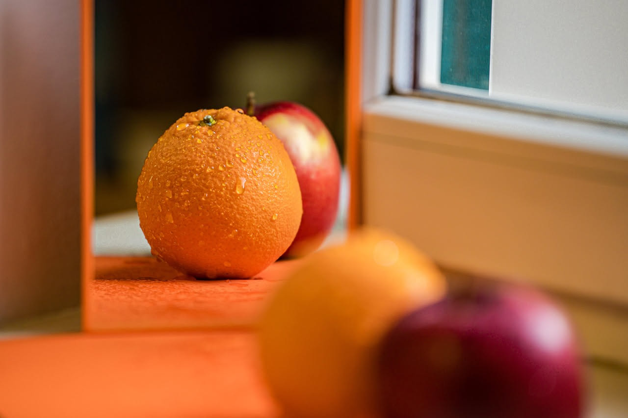 Limoni e arance freschi in una ciotola bianca accanto a una finestra illuminata dal sole del mattino, con vapore leggero che sale da una tazza in sottofondo