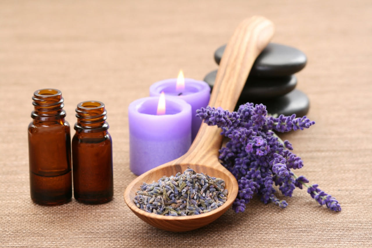 Pediluvio in una bacinella di ceramica bianca con acqua calda, bicarbonato visibile sul fondo, rami di lavanda fresca poggiati sul bordo e due piedi in ammollo